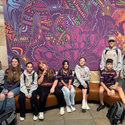 Kickstart students pose in front of RAP artwork